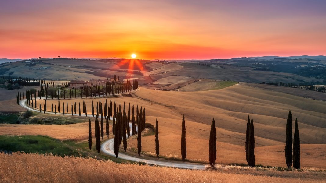 a fenced off road with a sunset in the background